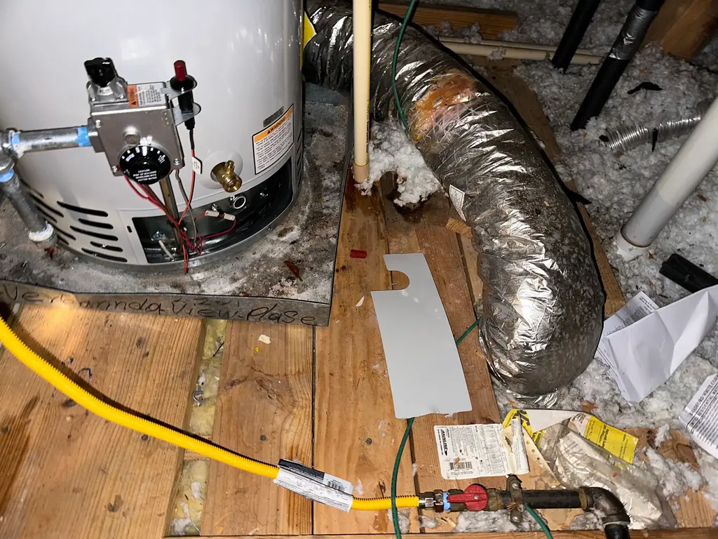 Water heater installation in an attic with gas line and venting work visible