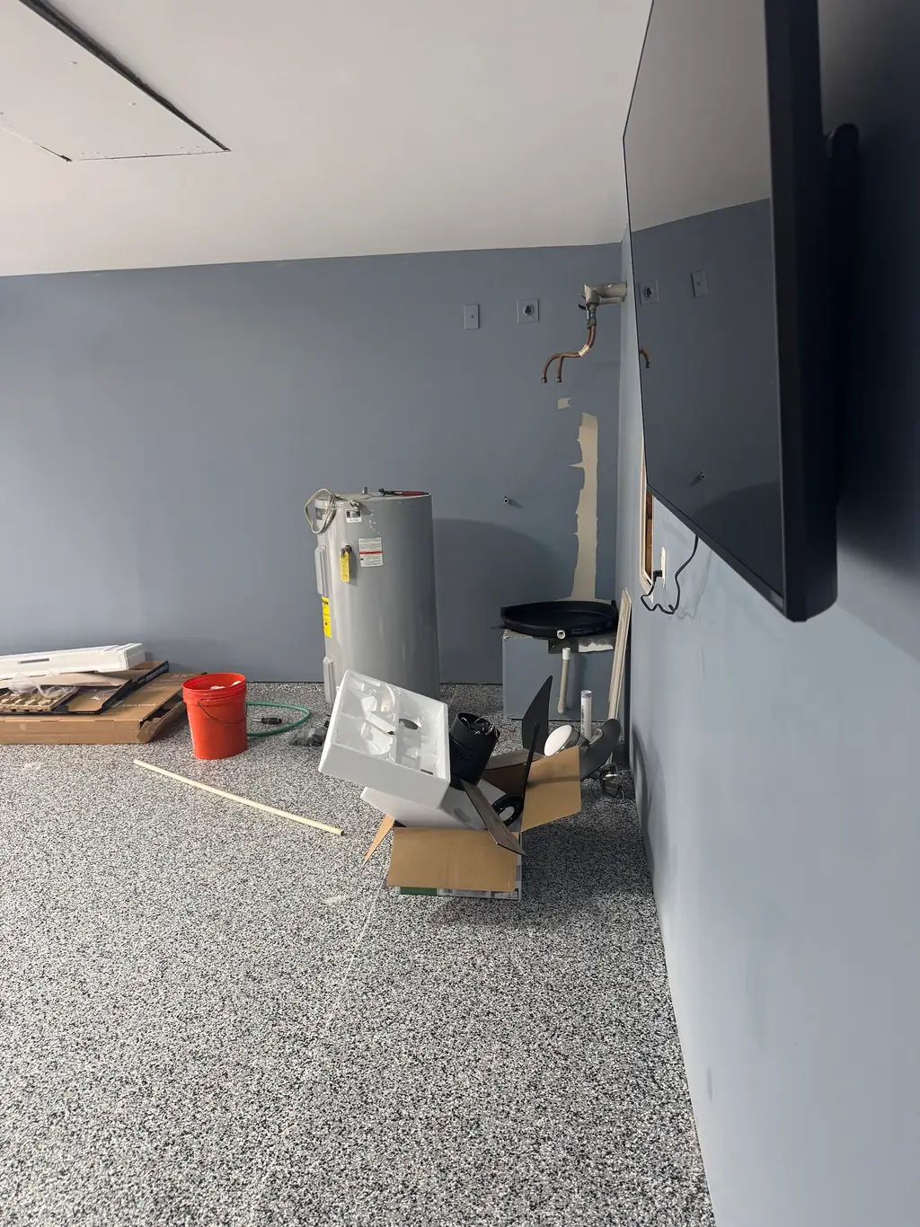Water heater being swapped out in a garage utility area, mid installation